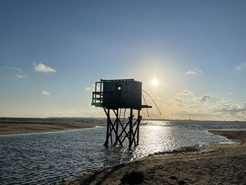 Lifeguard hut on beach against sky during sunset