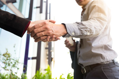 Midsection of businessman holding hand with colleague