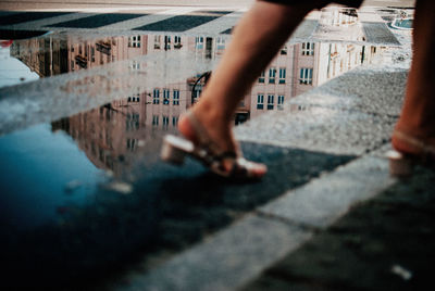 Low section of woman walking on wet street