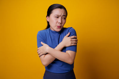 Boy standing against yellow background