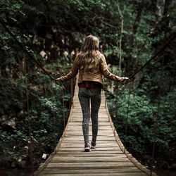 Rear view of woman walking on footbridge