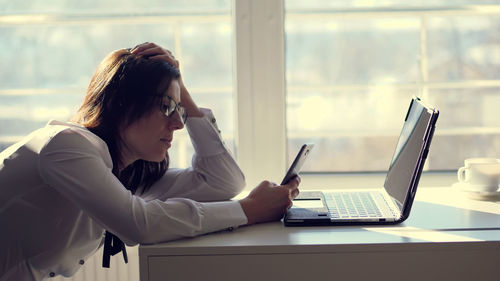 A young female clerk office worker browses social networks on a mobile phone, during her work day