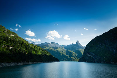 Scenic view of lake and mountains against blue sky