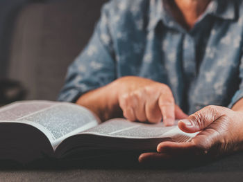 Midsection of man reading book on table