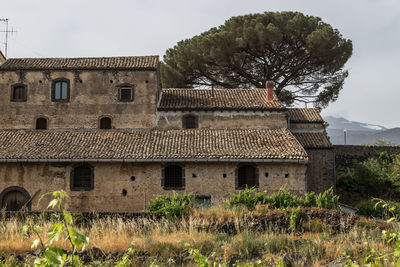 Old house on field by building against sky