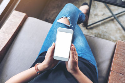 Low section of woman using mobile phone while sitting at home