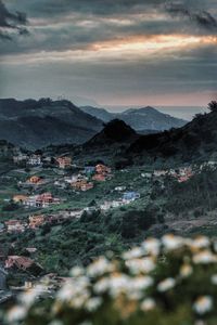 Houses in town by mountains against cloudy sky