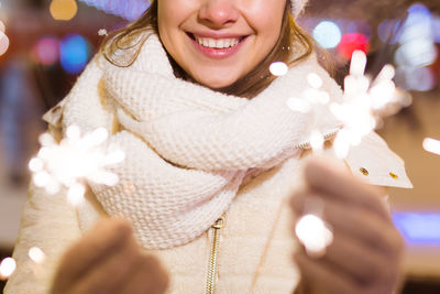 Midsection of woman holding sparkler outdoors