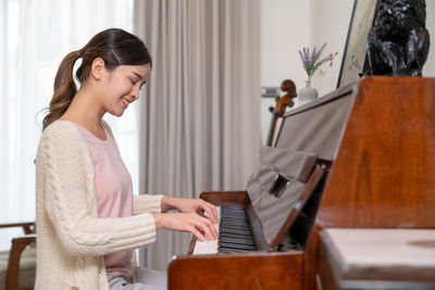 Side view of woman using laptop at home