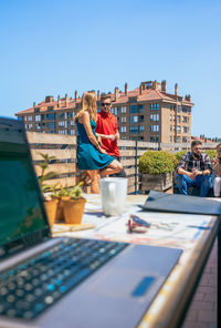 Couple talking in coffee break on office rooftop next to their colleagues