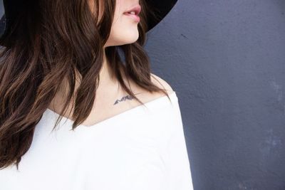 Midsection of woman standing against white wall