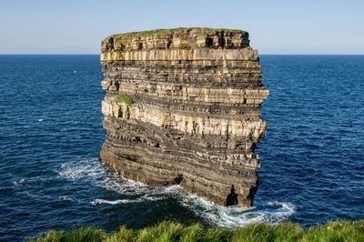 Cliff rock formation by sea against sky