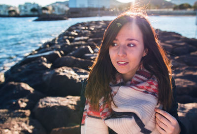 Woman standing on rocks against river during sunny day