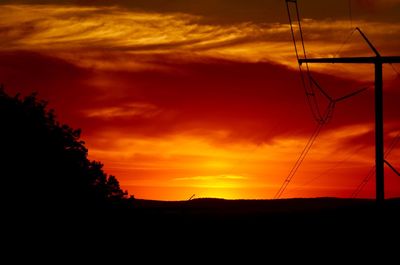 Low angle view of silhouette landscape against dramatic sky during sunset