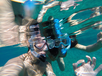 Couple showing ok sign while snorkeling in sea