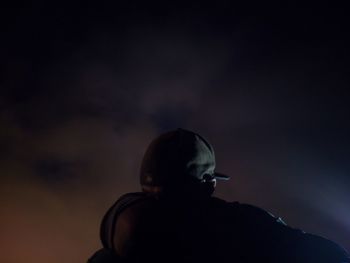 Rear view of silhouette man standing against dark sky