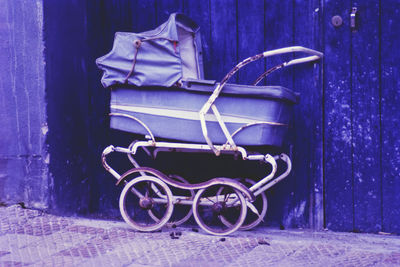 Old purple pram against wooden closed door