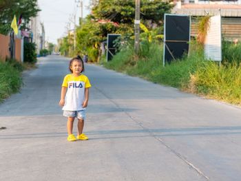 Portrait of boy on road against building in city