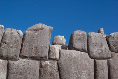 Low angle view of stone wall against clear blue sky