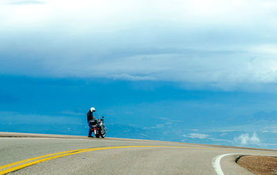 Person standing with motorcycle at roadside