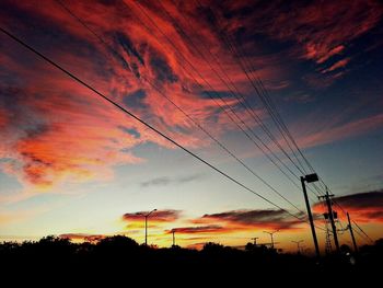 Low angle view of electricity pylon at sunset