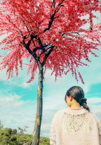 Rear view of woman standing against cherry tree