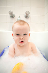 Close-up portrait of shirtless baby boy in bathtub at bathroom