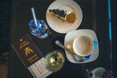 Directly above shot of passport with drinks and dessert on table