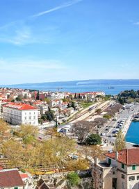 High angle view of buildings and sea against blue sky