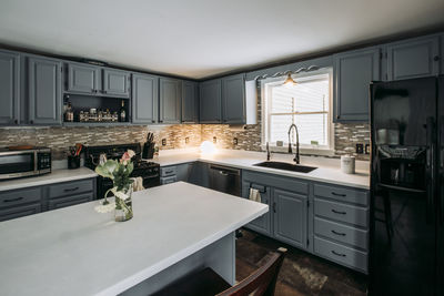 Gray and white kitchen interior with black refrigerator and flowers