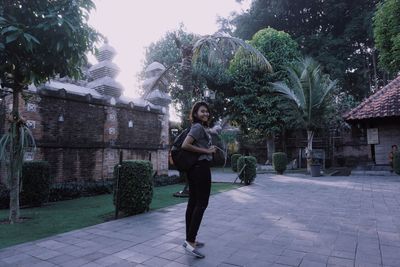 Full length portrait of young woman on footpath