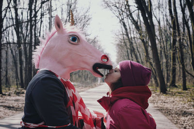 Side view of man wearing mask standing with woman on road in forest