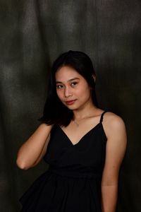 Portrait of young woman standing against wall