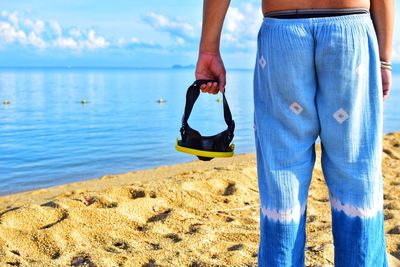 Low section of man standing on beach