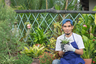 Portrait of smiling young man holding flowering plants