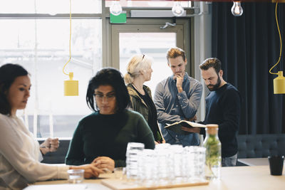 Business colleagues reading book in brightly lit office