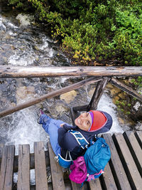 High angle portrait of woman on railing against trees