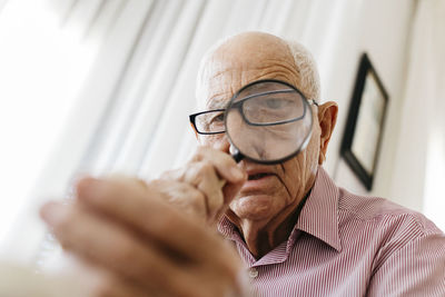 Retired senior male looking through magnifying glass at fossil