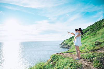 Rear view of woman standing against sea against sky