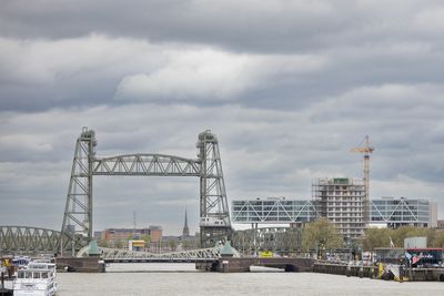 Bridge over river against cloudy sky