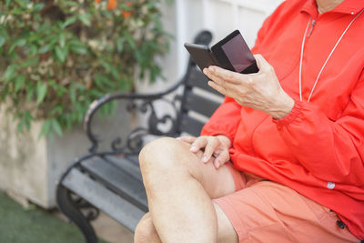 Midsection of man using mobile phone while sitting outdoors