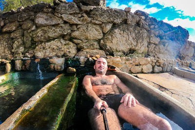 Portrait of shirtless man lying in hot spring