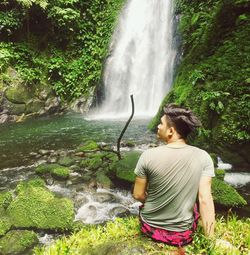 Man sitting against waterfall