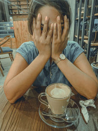 Portrait of woman with drink sitting on table