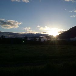 Scenic view of silhouette field against sky at sunset