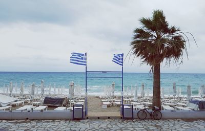 Deck chairs on beach against cloudy sky