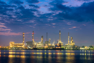 Illuminated factory against sky at night