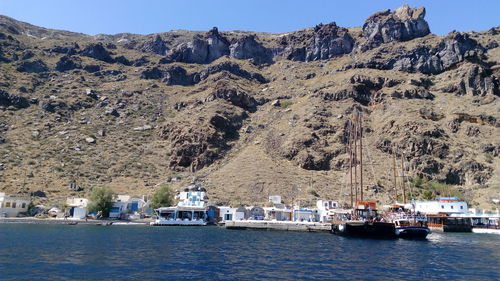 Boats moored on sea by mountains against sky