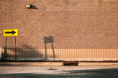 Directional sign on sidewalk against wall