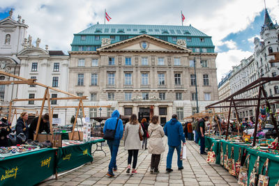 Rear view of people on street against buildings in city